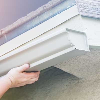 Worker installing new seamless gutters on the fascia of a home